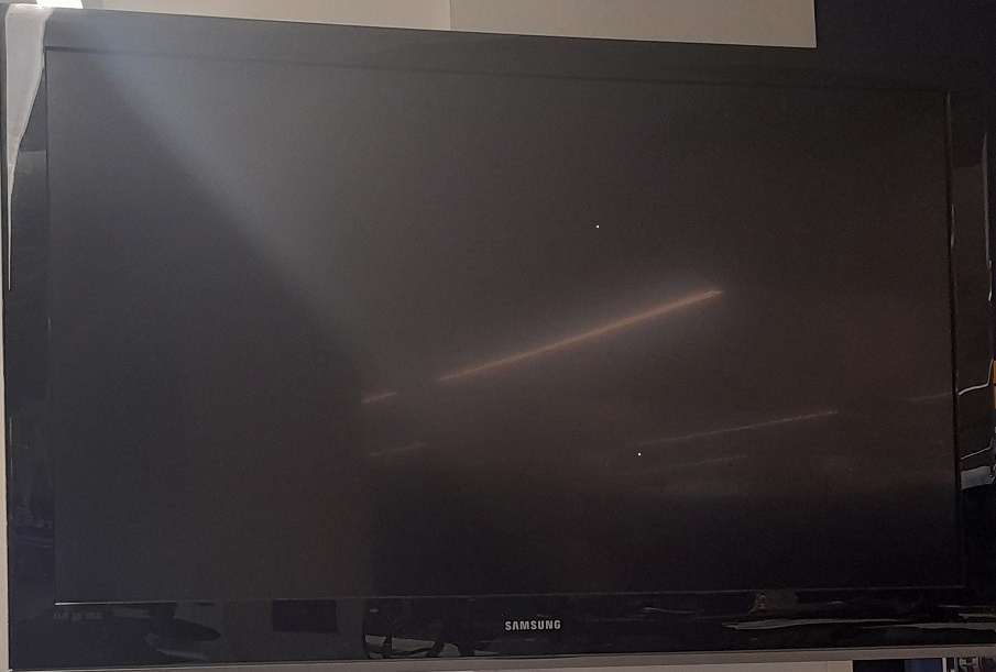 A black coloured samsung television hanging on a wall