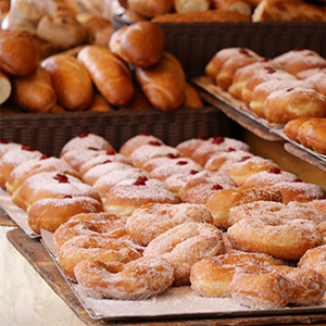 some doughnuts on a tray and some bread behind