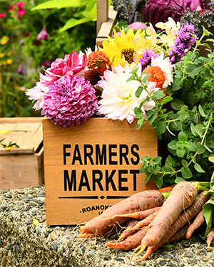 A wooden box with farmers market boldly written on it with flowers inside